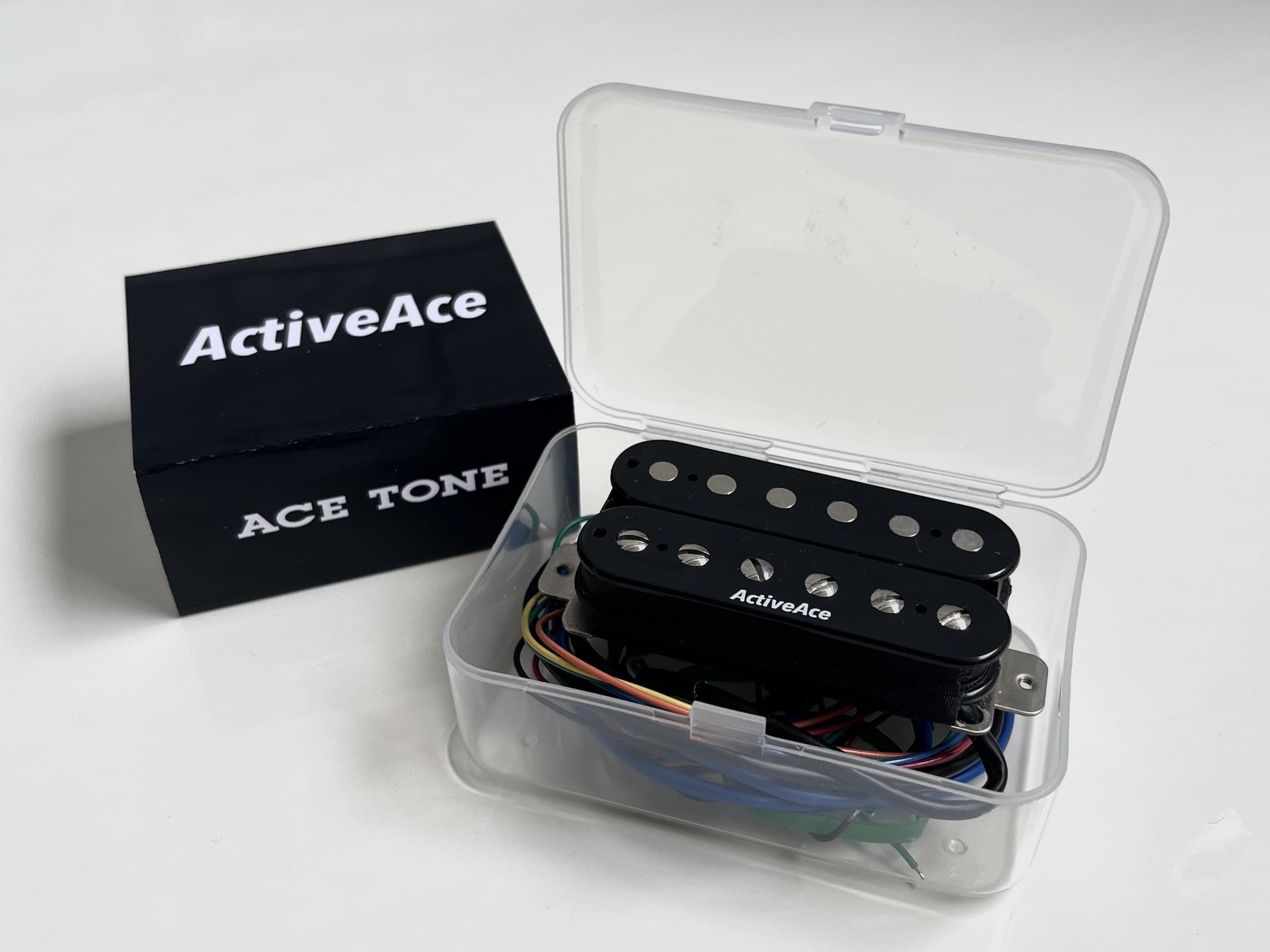 ActiveAce pickup in its opened retail case beside the sleeve, which reads ActiveAce on the face and ACE TONE on the side